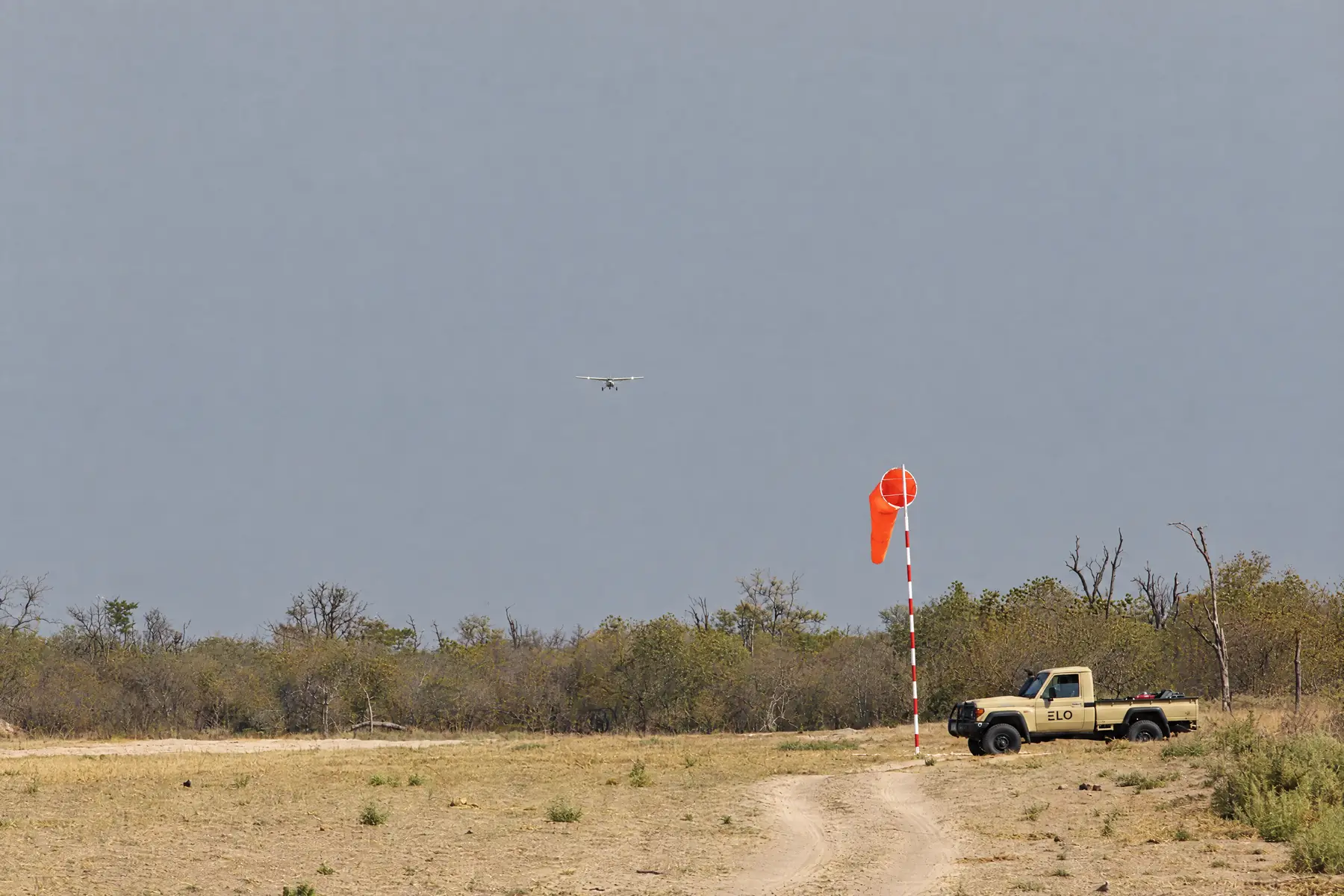 A light aircraft landing on the bush airstrip beside the windsock