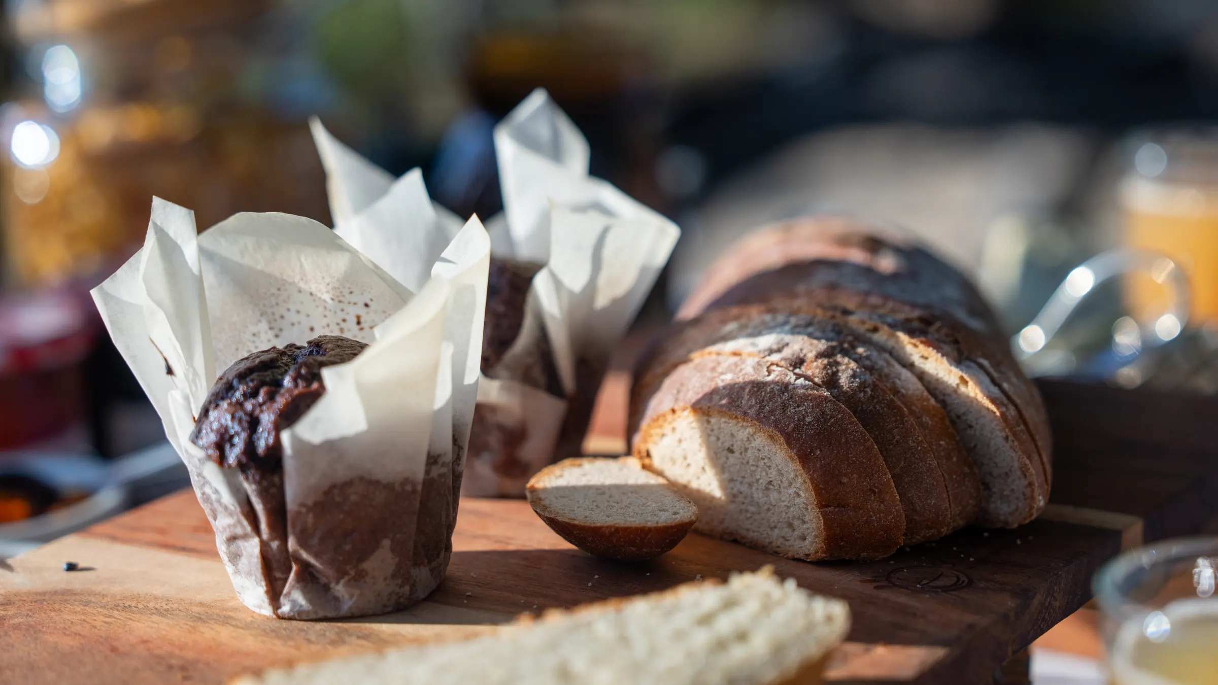 Bread and muffins in paper on a wooden board, in the morning light