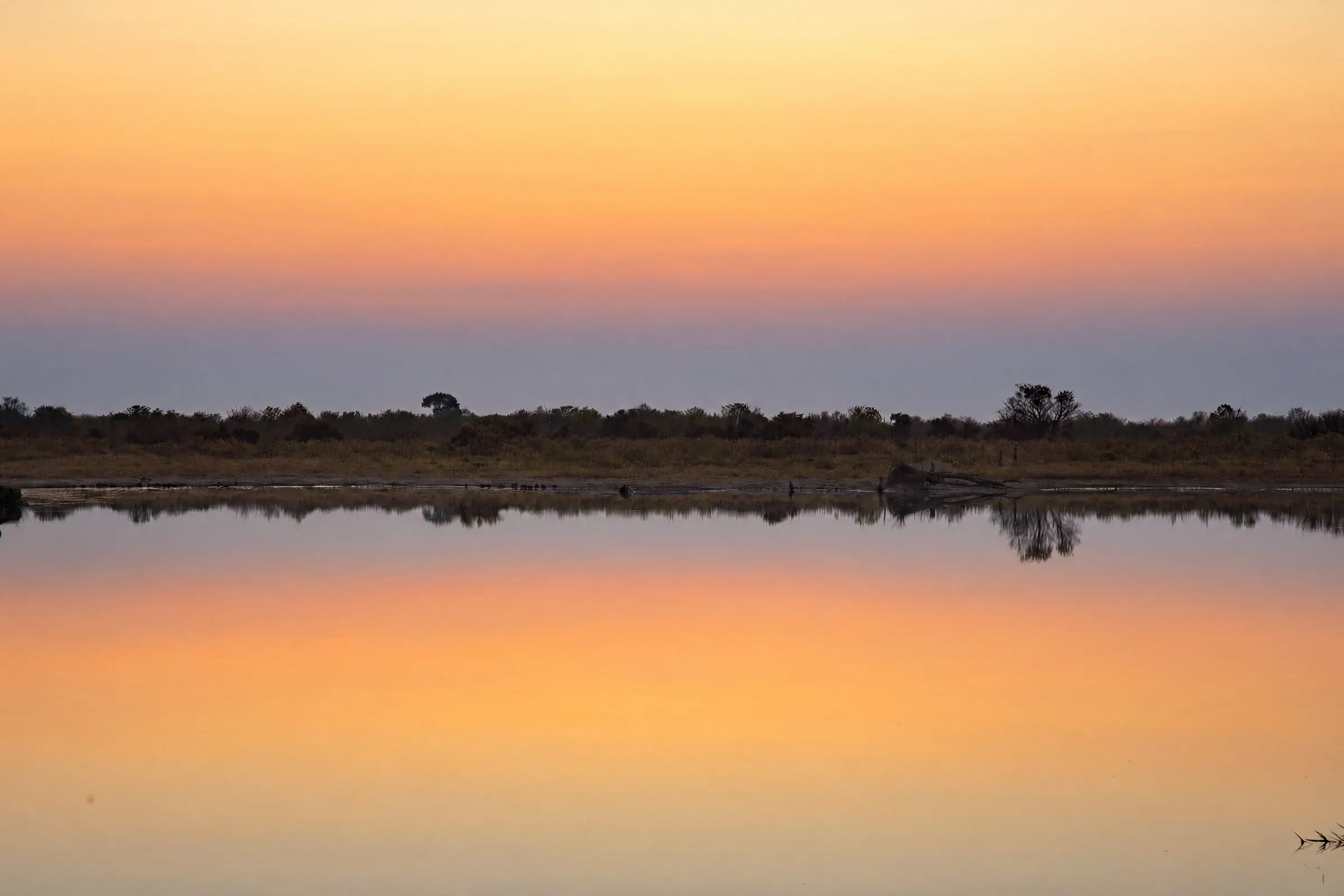 A still lagoon reflecting the orange sky after sunset