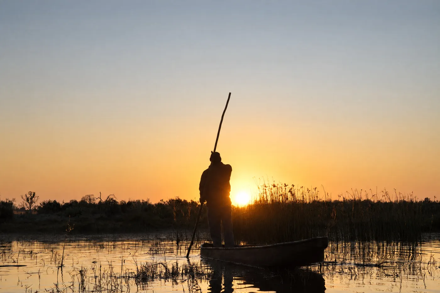 A mokoro poler at sunset