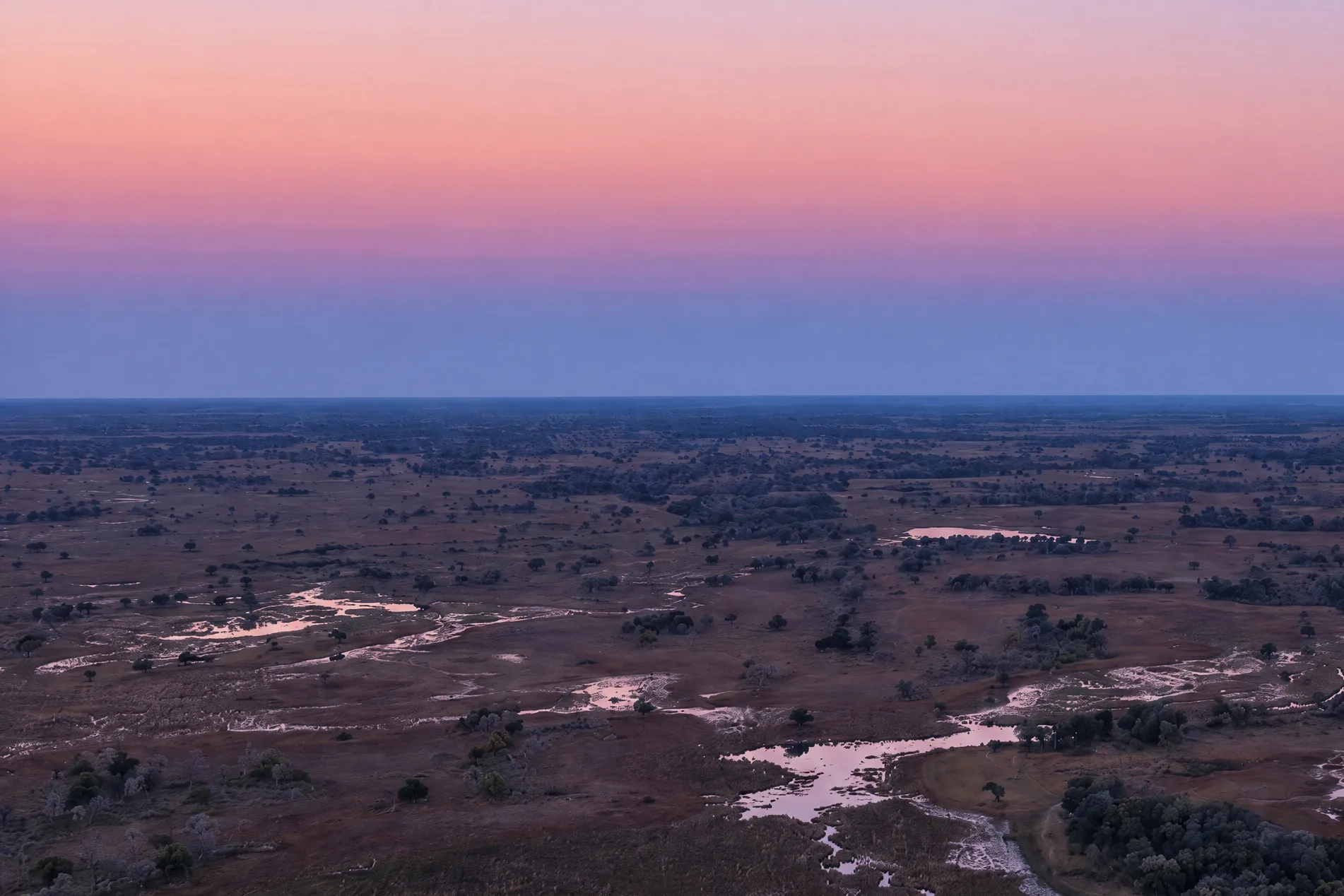 The concession at dusk from high above, floodplains, tree islands and channels running to the horizon