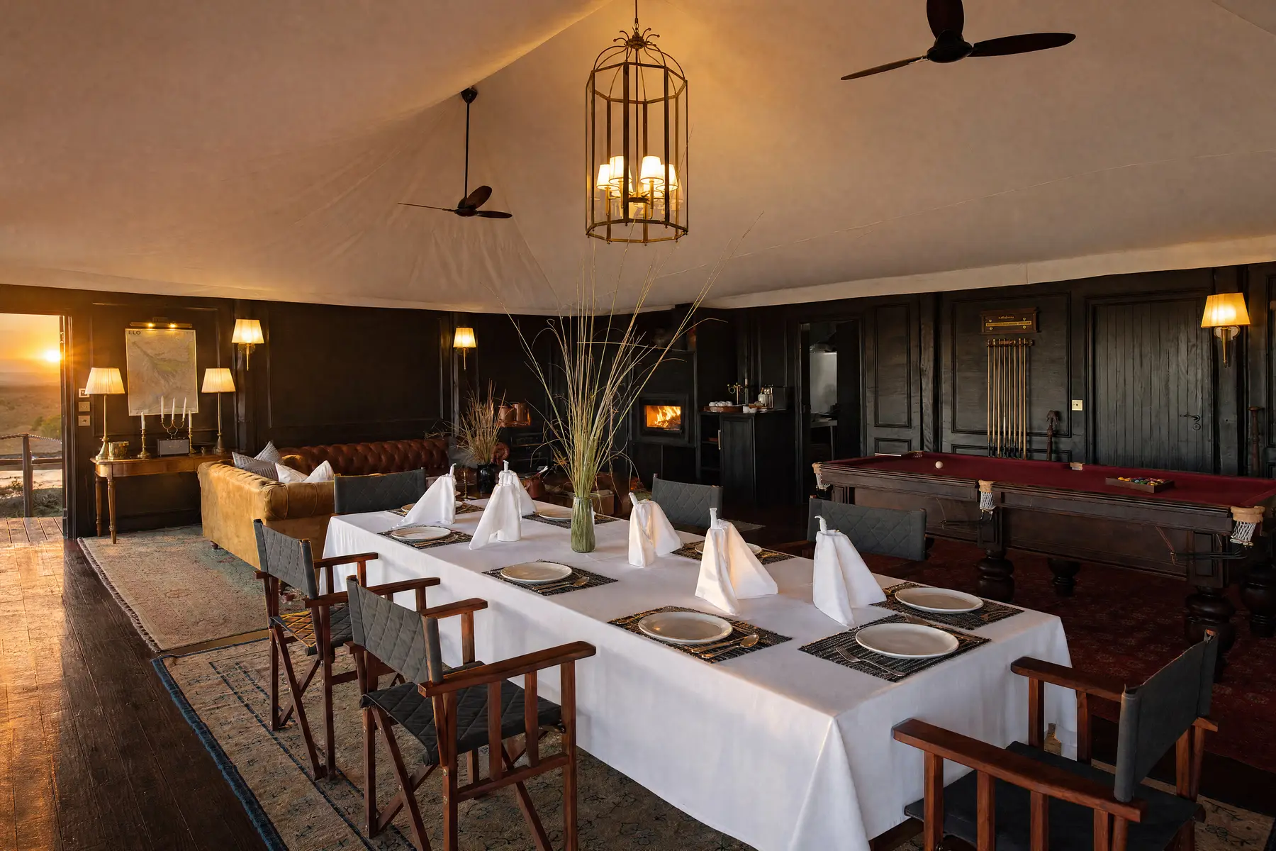 A table laid in the lounge house under a lantern, the billiard table behind