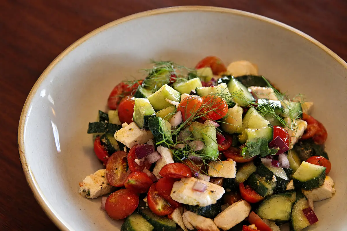 A bowl of cherry tomatoes, cucumber and feta with fresh herbs