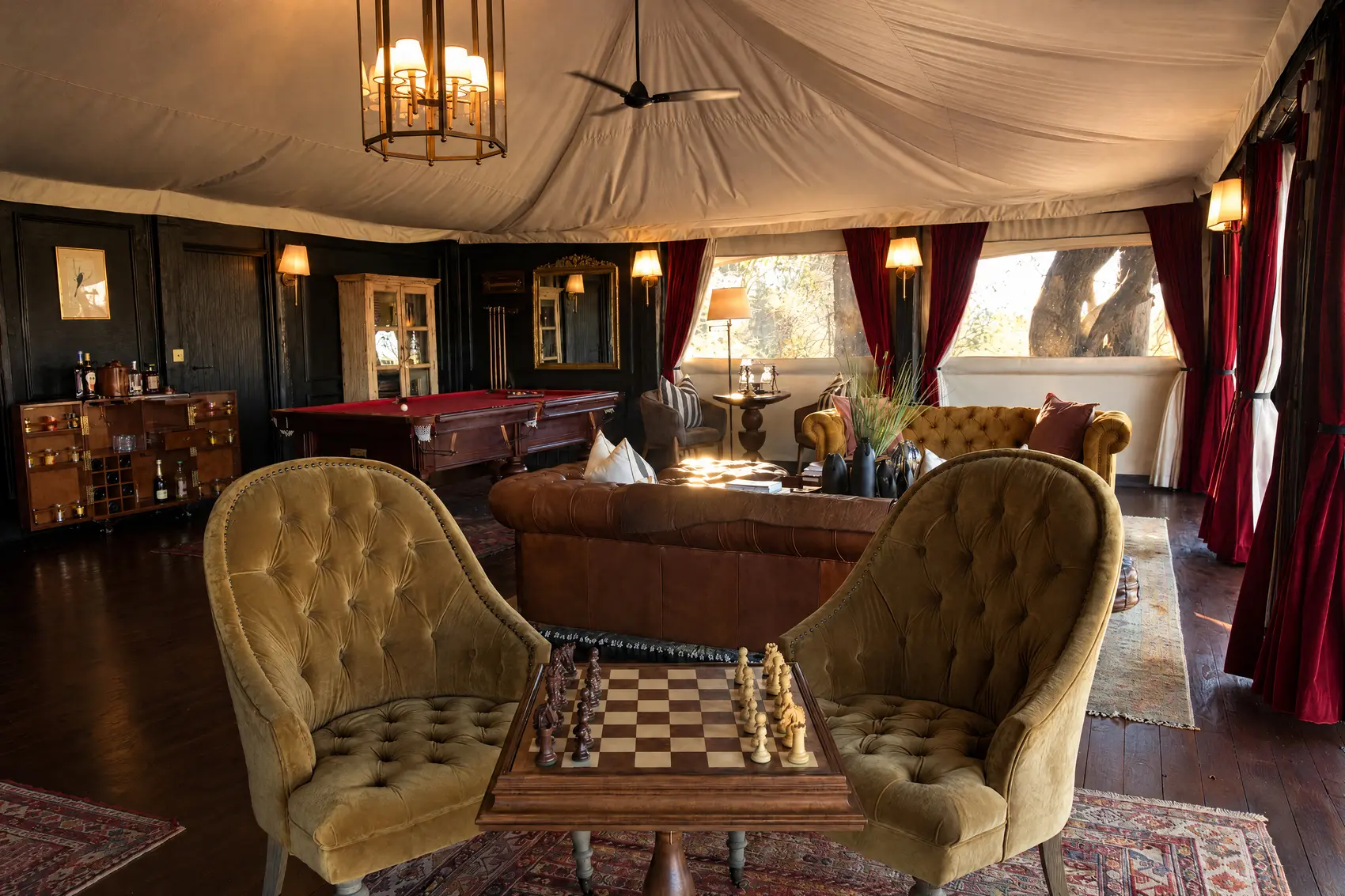 Two velvet armchairs and a chessboard in the lounge house, the billiard table behind