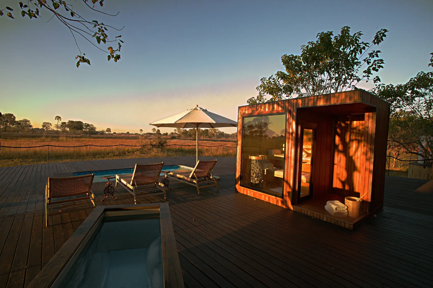 A timber and glass sauna on the deck beside the plunge pool, at sunrise