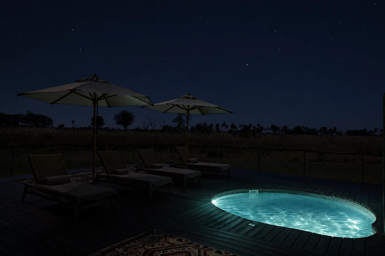The pool lit from within at night, the parasols dark against the stars
